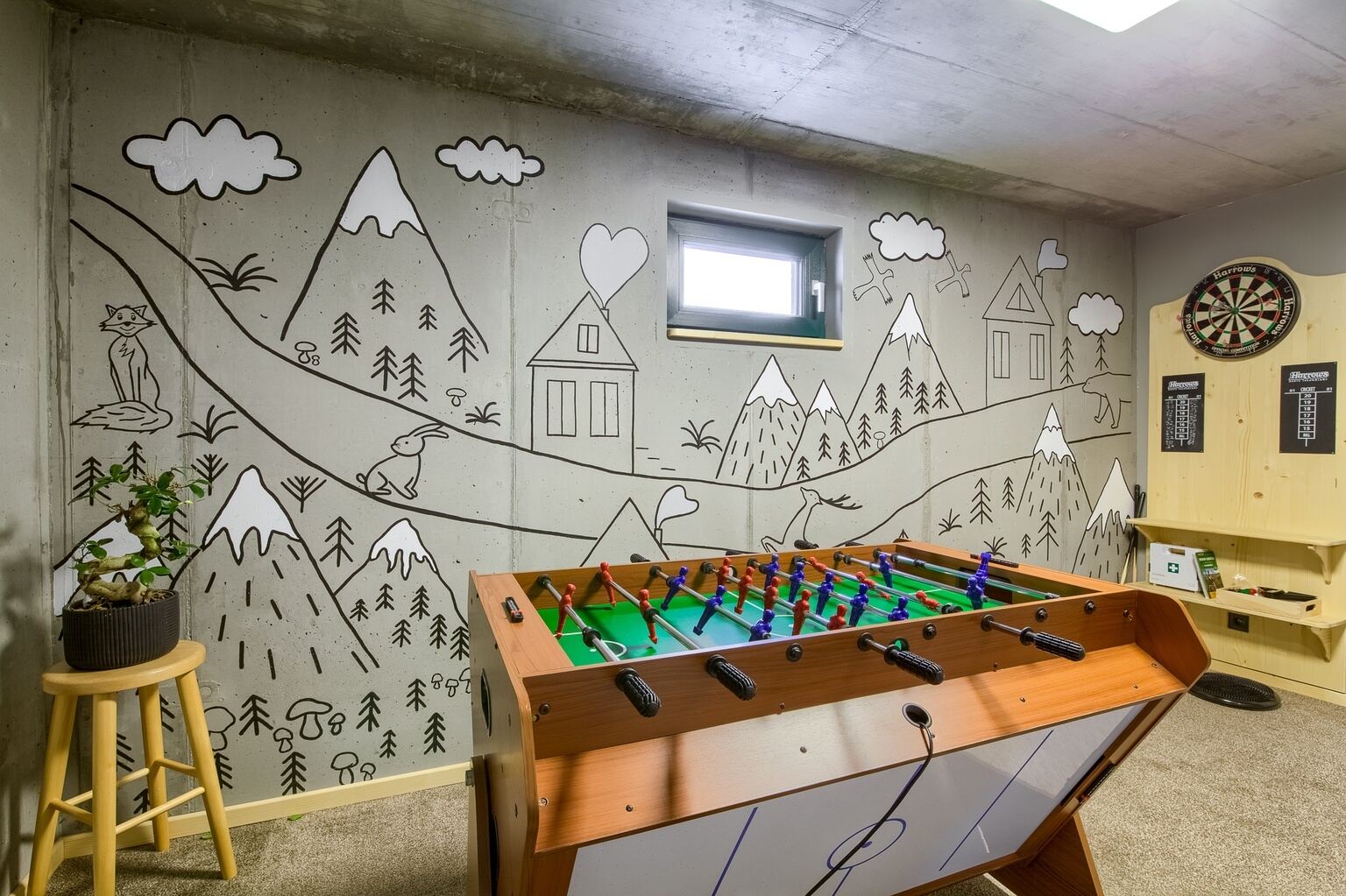 Playroom with a mountain mural, table football and darts