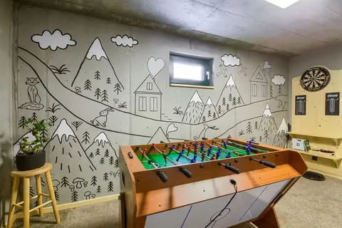 Sala zabaw z muralem górskim, piłkarzykami i dartem