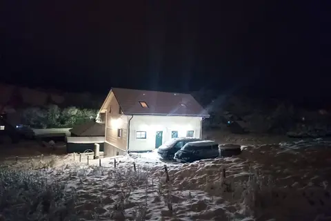 Dom Dubáčik nocą z zaparkowanymi samochodami